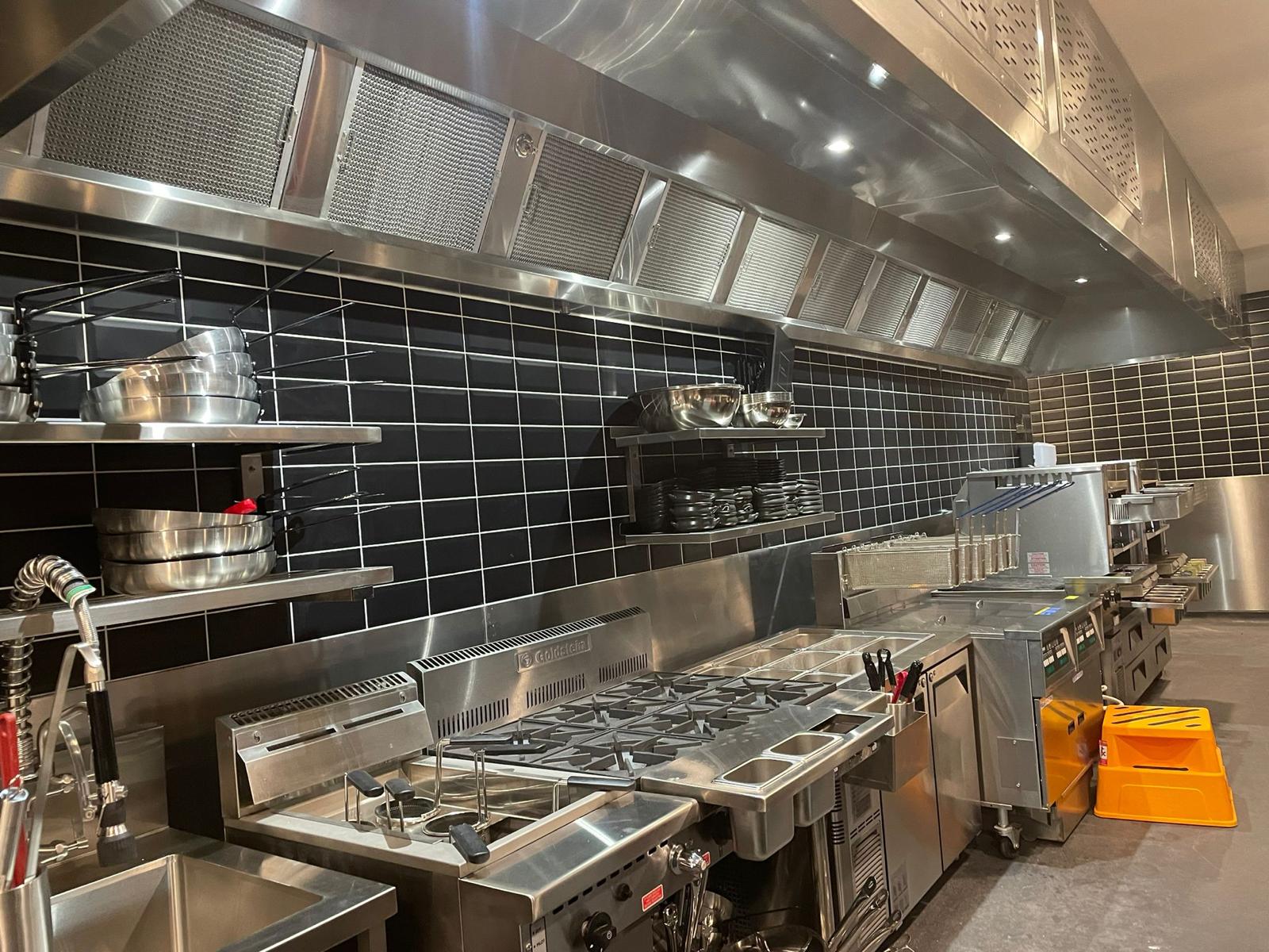 Commercial kitchen equipment beneath a stainless exhaust canopy